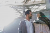 Low angle of smiling couple looking at each other at urban scene — Stock Photo