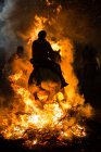 Side view of horse riding through bonfire in a purification ritual — Stock Photo