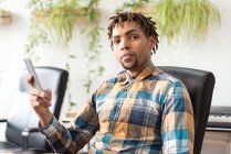 Man with phone sitting in office chair and looking at camera — Stock Photo