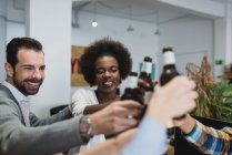 Portrait of people clanging bottles in office while teambuilding — Stock Photo