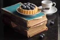 Pastel de arándanos sobre libros antiguos - foto de stock