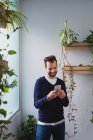 Portrait of smiling man using smartphone near window in office — Stock Photo