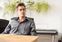 Confident businessman sitting at workplace in office and looking aside — Stock Photo