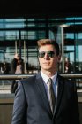 Елегантний бізнесмен з сонцезахисними окулярами позує на центральній вулиці — стокове фото