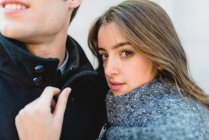 Portrait of brunette girl leaning on mans shoulder and looking at camera — Stock Photo