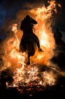 Rear view of horse riding through bonfire in purification ritual at night — Stock Photo