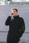 Ritratto di uomo che parla telefono sopra il muro grigio in strada — Foto stock