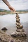 Crop hand stretching to stone tower — Stock Photo