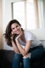 Brunette woman sitting on sofa and looking at camera. — Stock Photo