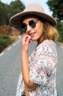 Chica bonita en sombrero posando en la carretera - foto de stock
