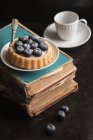 Gâteau aux myrtilles sur de vieux livres — Photo de stock