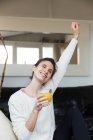 Portrait of brunette woman holding glass of orange juice and stretching with eyes closed — Stock Photo
