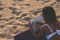 Mujer leyendo libro en la playa - foto de stock