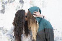 Girlfriends kissing against wall — Stock Photo