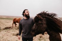 Homme caressant cheval sauvage icelandique — Photo de stock