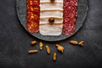 Salami und Käsescheiben auf grauem Teller — Stockfoto