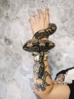 Serpente strisciare intorno tatuato mano — Foto stock