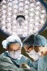 Хирурги, работающие под лампой — стоковое фото