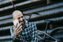 Сміється молодий чоловік за допомогою телефону — стокове фото