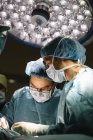 Cirurgiões operação de processamento sob lâmpada — Fotografia de Stock