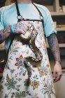 Tattooed man wearing apron holding snake. — Stock Photo