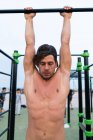 Мускулистый человек тренируется на подбородке вверх бар — стоковое фото