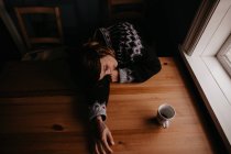 Жінка лежить на столі з чашкою — стокове фото