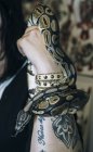Змея ползает вокруг татуированной руки с браслетом — стоковое фото