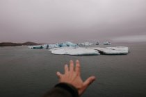 Crop hand outstretched to glacier — Stock Photo