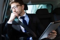 Handsome man in car with tablet — Stock Photo