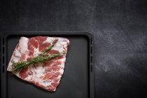 Directly above view of raw pork ribs with herbs on baking tray — Stock Photo