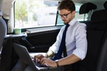 Uomo d'affari che lavora con laptop in auto — Foto stock