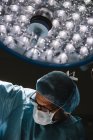 Cirurgião em máscara de pé à luz da lâmpada — Fotografia de Stock