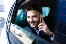 Homme d'affaires souriant parlant au téléphone dans la voiture — Photo de stock