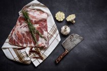 Directly above view of raw pork ribs with herbs and spices on towel — Stock Photo