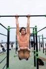 Uomo muscolare che si esercita sul mento-up bar — Foto stock
