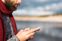 Bearded male using phone in nature. — Stock Photo