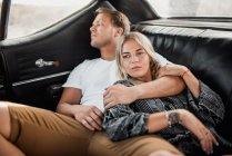 Горизонтальный снимок спокойного мужчины и женщины, лежащих в машине и обнимающихся — стоковое фото