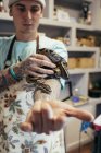 Татуйований чоловік у фартуху тримає велику змію на руці — стокове фото