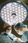 Lamp over surgeons providing operation — Stock Photo