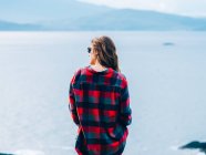 Chica de pie contra el lago brumoso - foto de stock