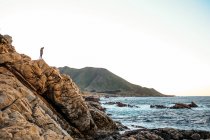 Мужчина, стоящий на скале и любующийся водным пейзажем — стоковое фото