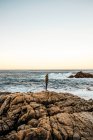 Uomo in piedi sulla costa rocciosa — Foto stock