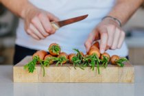 Mains avec couteau tranchant les carottes — Photo de stock