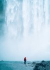 Person steht gegen mächtigen Wasserfall — Stockfoto