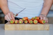 Persona que se prepara para cortar zanahorias - foto de stock