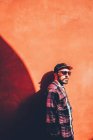 Uomo in posa sulla parete rossa illuminata dal sole — Foto stock