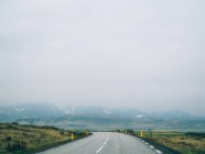Estrada que leva a colinas nebulosas — Fotografia de Stock