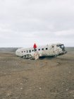 Женщина стоит на обломках старого самолета — стоковое фото
