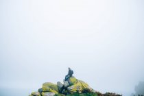 Hombre sentado en la formación de rocas . - foto de stock
